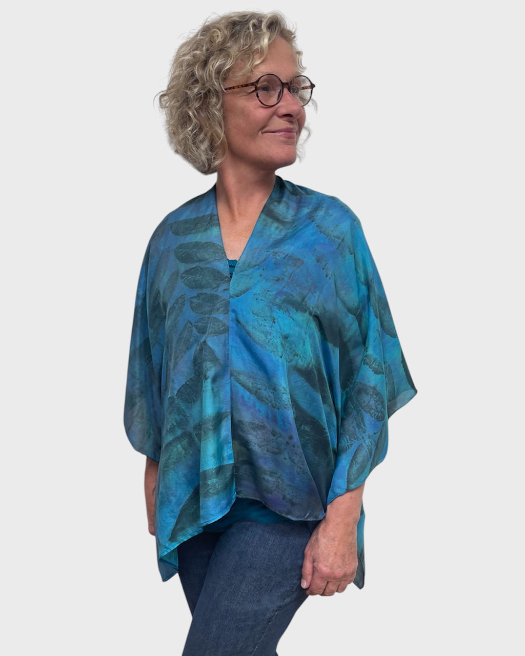Turquoise eco print silk poncho worn with V-neck centered in front, close side view