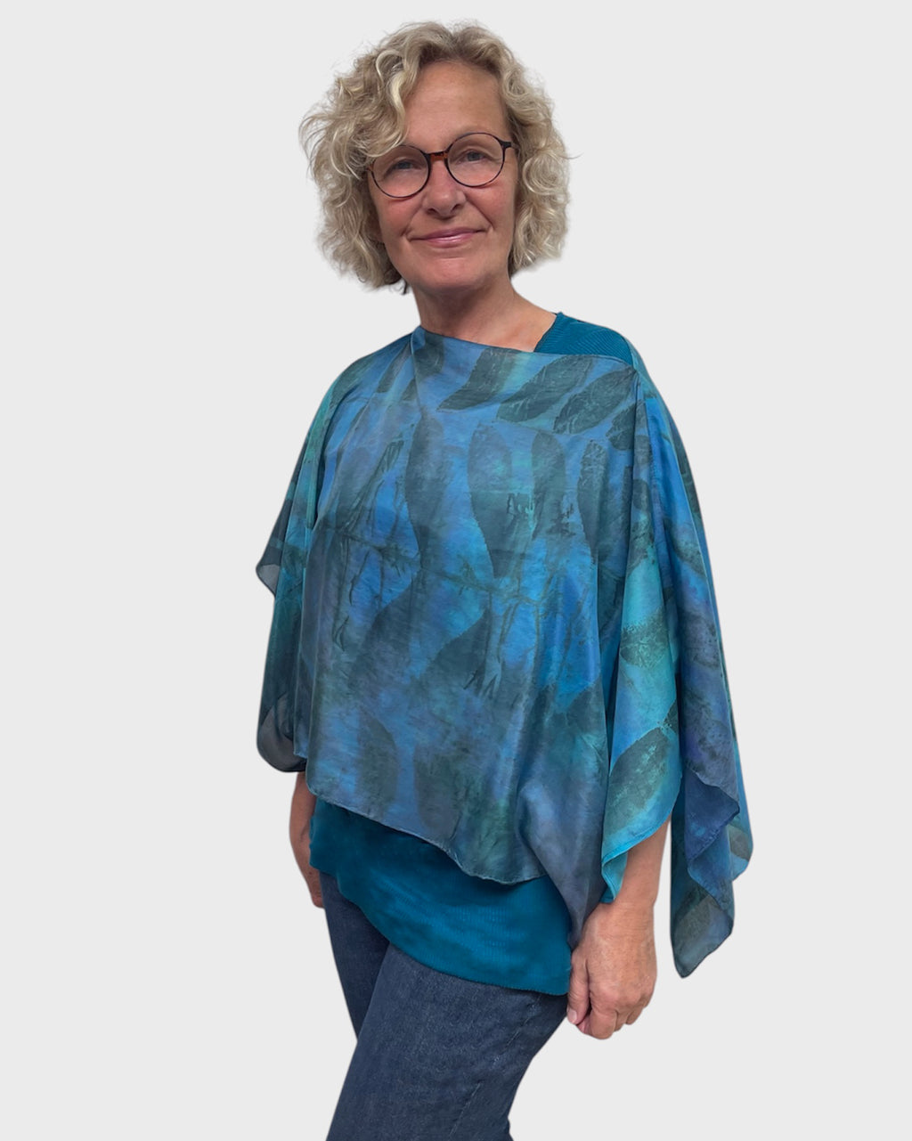 Woman wearing turquoise silk poncho with boat neck styling, front and center view