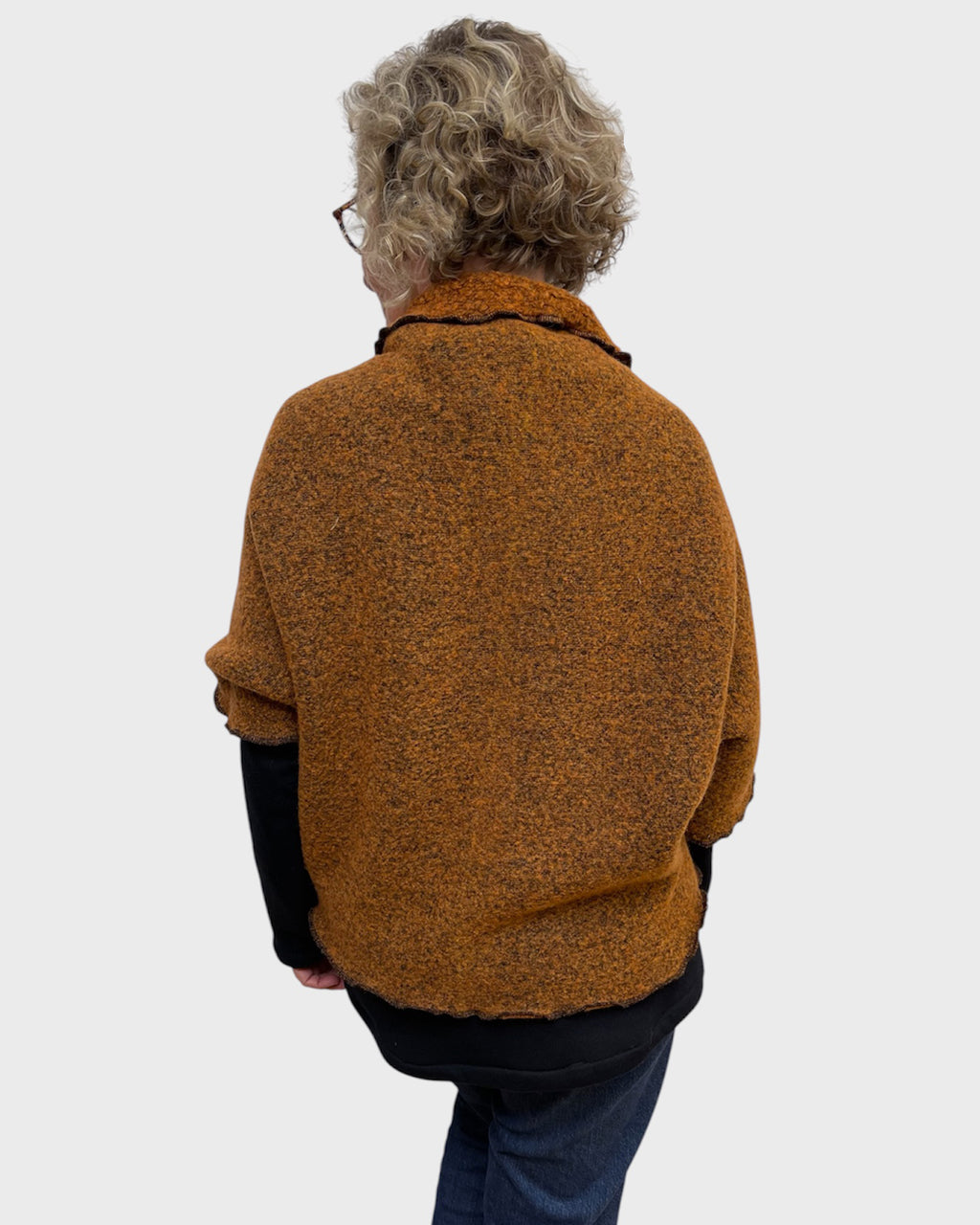 Back of pumpkin and black wool polyester shrug with rounded hem, one size
