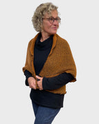 Woman fastening the one button on a pumpkin and black wool polyester shrug