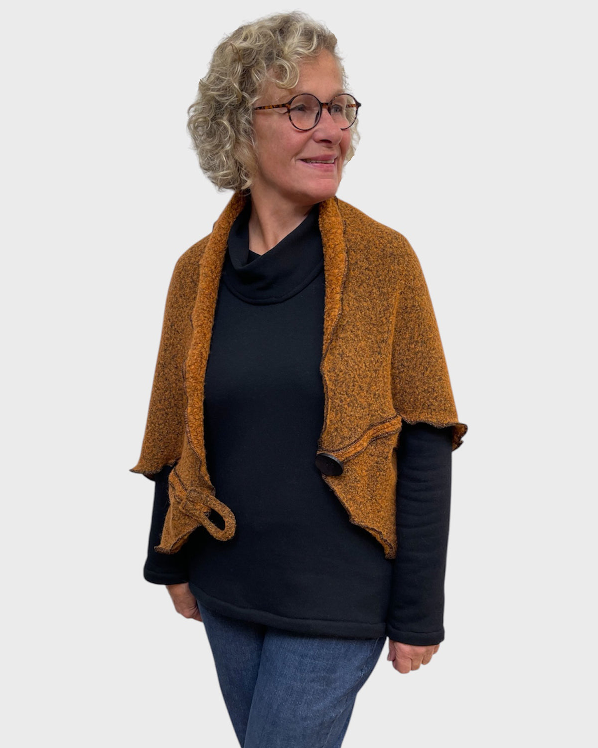 Pumpkin black stretch shrug worn open over a black cowl neck top and jeans