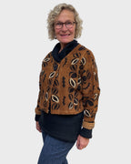 Rust black and white cotton mudcloth bolero jacket with one large black button over a black cowl neck top
